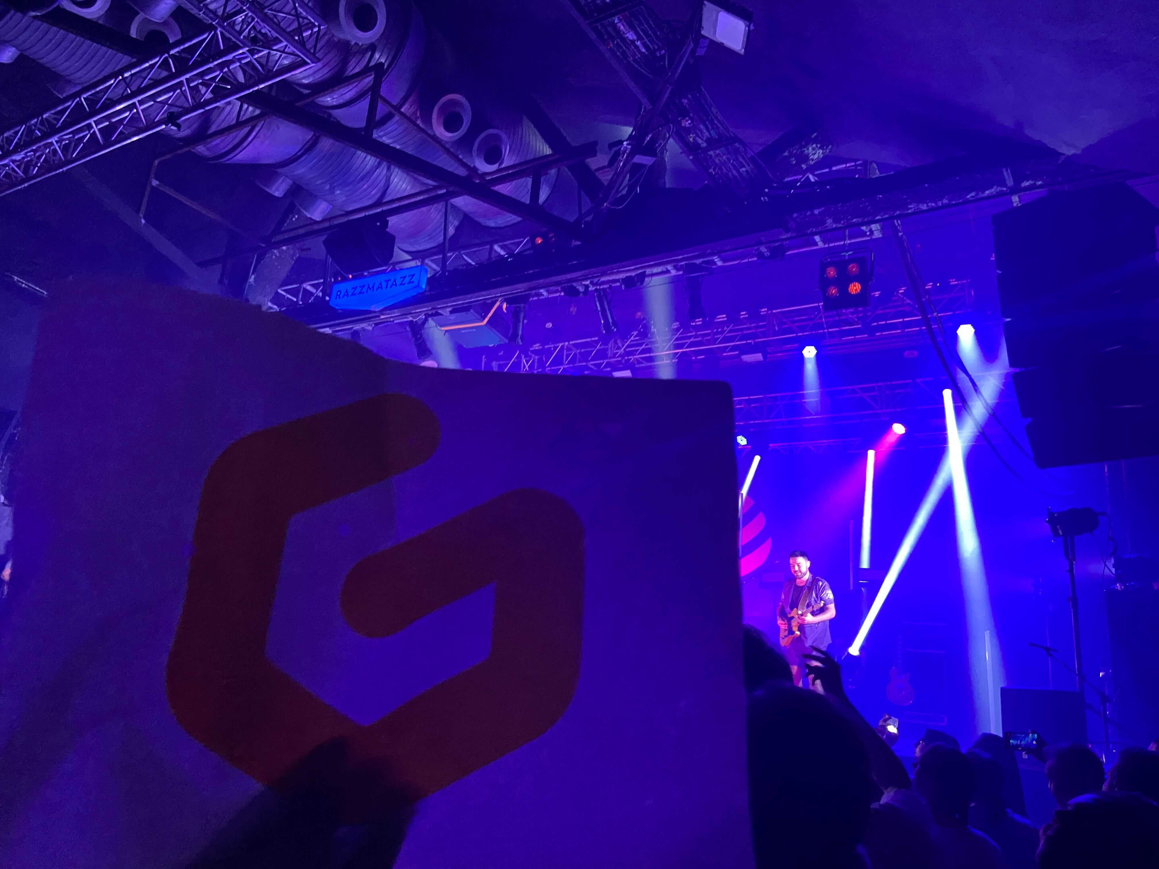 A gitpod sign in the crowd with Josep playing guitar in the background